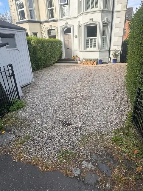 Worn gravel front drive with weeds and a broken edge before the work